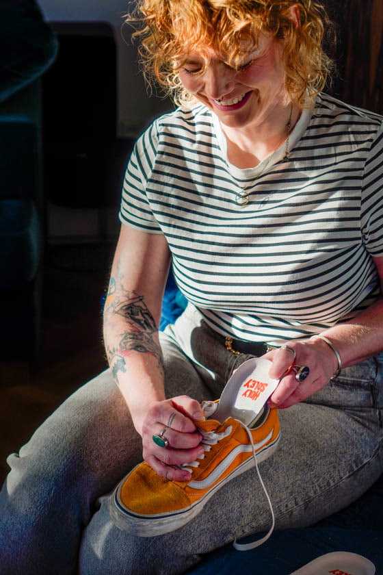 Lachende Frau legt eine Einlegesohle in einen Vans Schuh